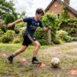 A young football player doing dribbling drills at home with cones in a garden, part of a home football training plan