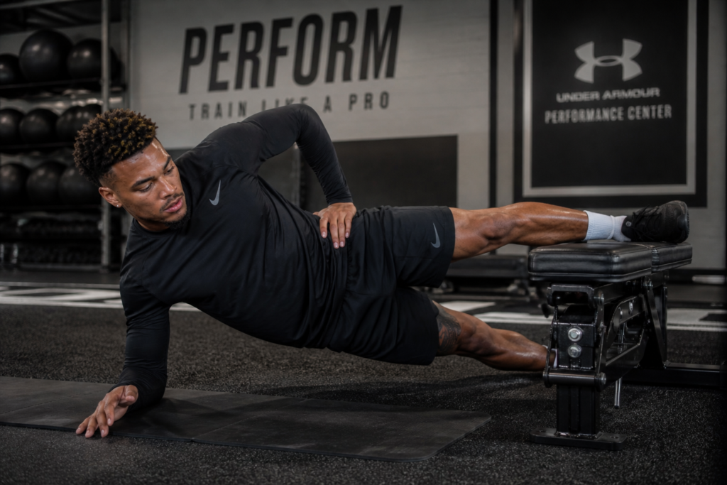 Football player performing best core exercises for football players with Copenhagen plank for groin strength.
