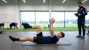Football player demonstrating best core exercises for football players with dead bug core exercise.