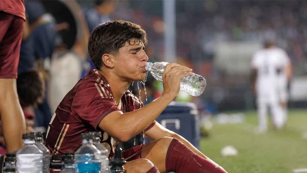 Football player drinking water during a match break on the sideline