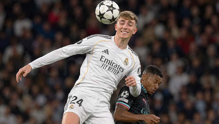 Dean Huijsen winning a high aerial ball in a Real Madrid-inspired white football kit during a match